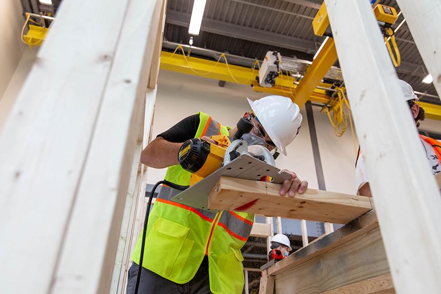 A Construction Management student cutting a piece of wood